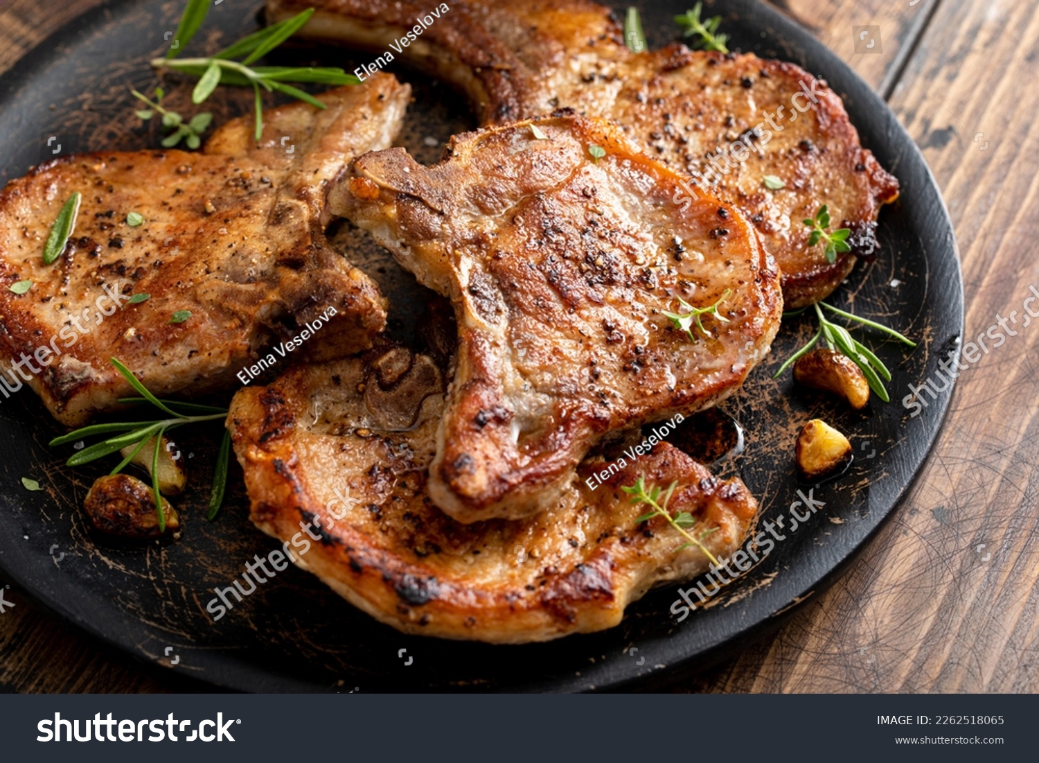 Pork chops grilled or seared with garlic and herbs bone in on a serving plate #2262518065