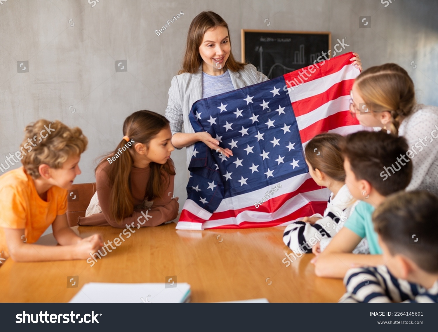 Geography lesson in school class - teacher talks about United States of America, holding a flag in his hands #2264145691