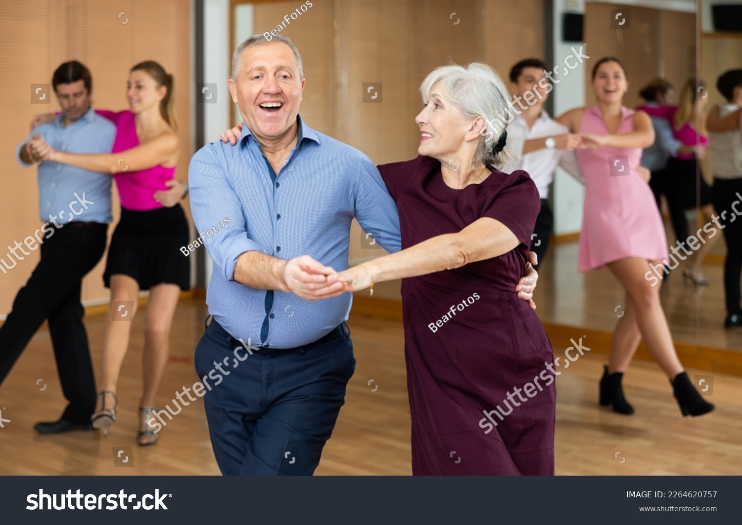 Happy older couple performing a paired ballroom dance in ballroom #2264620757