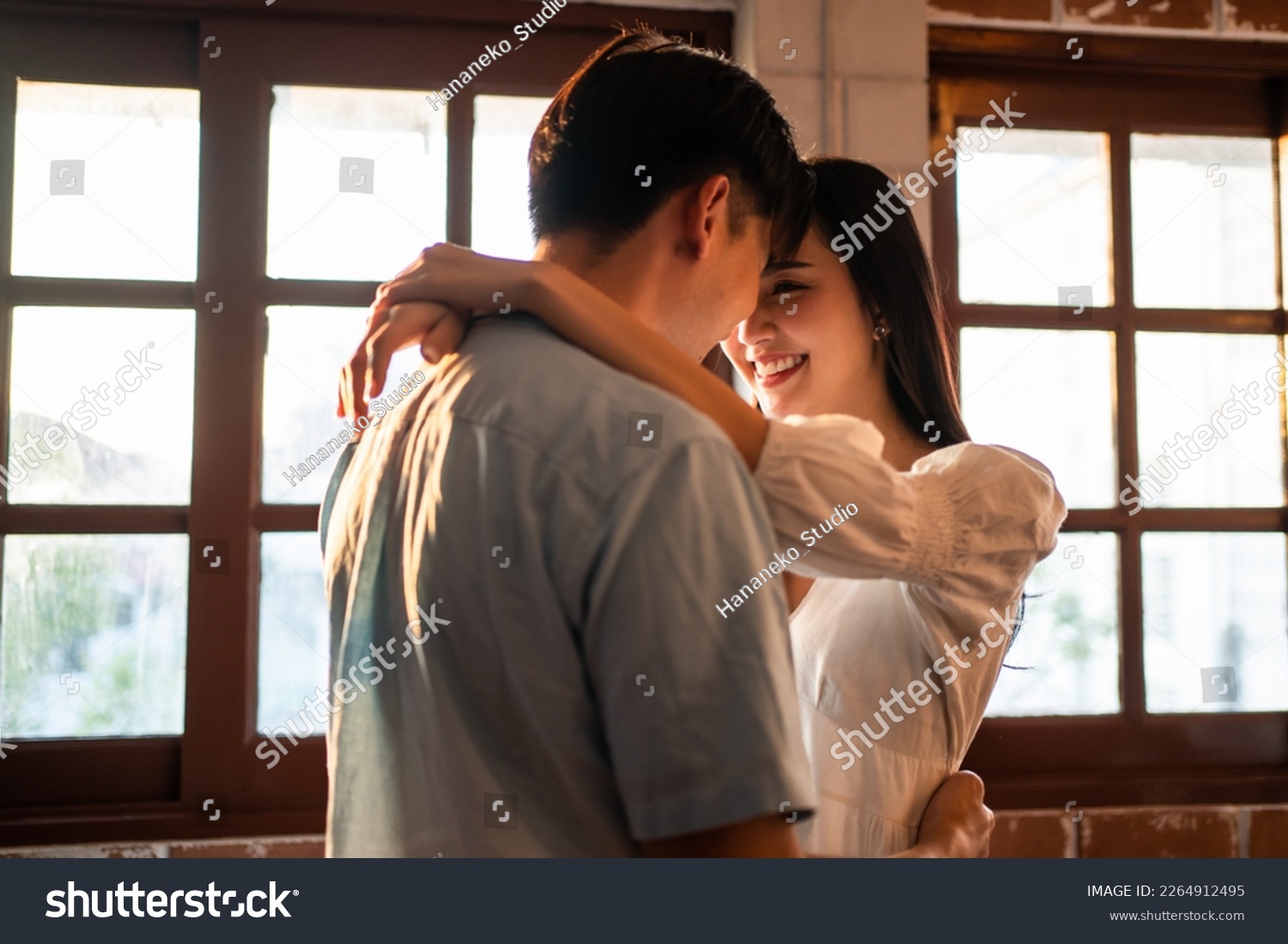 Asian young man and woman hugging each other in living room at home. Attractive romantic new marriage couple male and female spending time celebrate anniversary and valentine's day together in house. #2264912495
