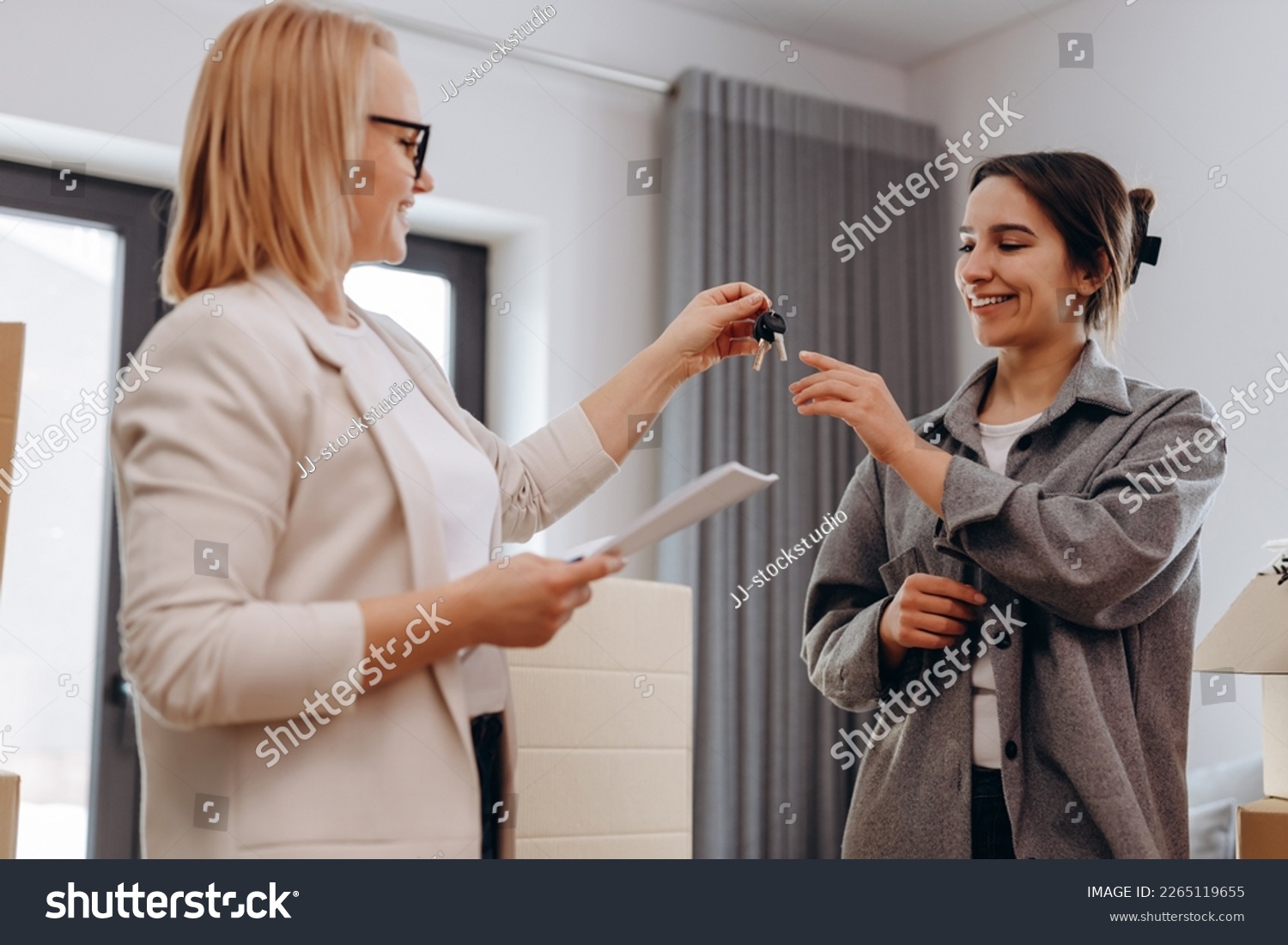Close up young female real estate agent giving keys to happy buyer, congratulating with purchasing apartment. Millennial woman taking in leasing new house, accommodation tenancy rental service concept #2265119655