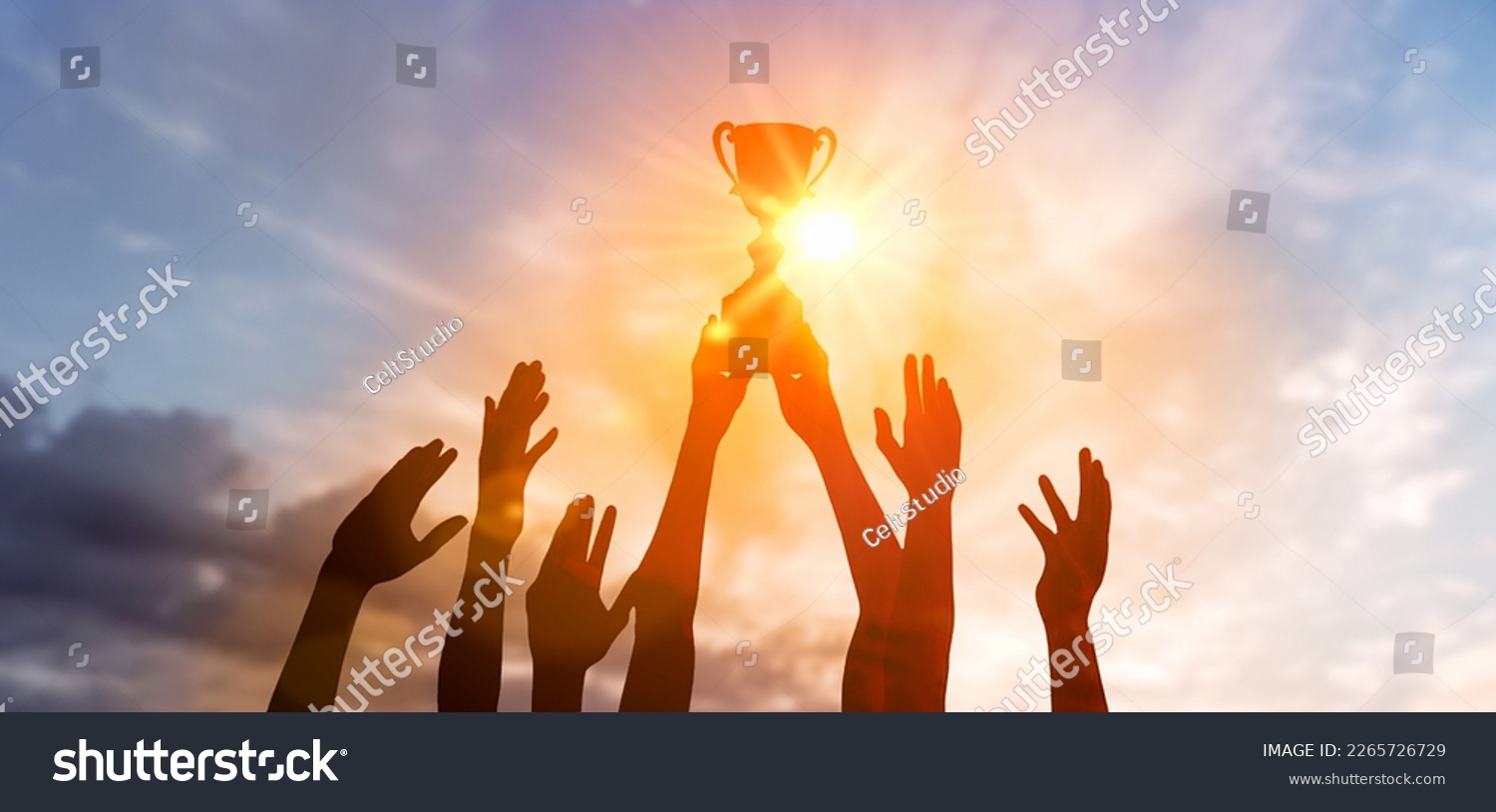 Success of teamwork, joint achievement of goal in business and life. Winning team is holding trophy in hands. Silhouettes of many hands in sunset. #2265726729