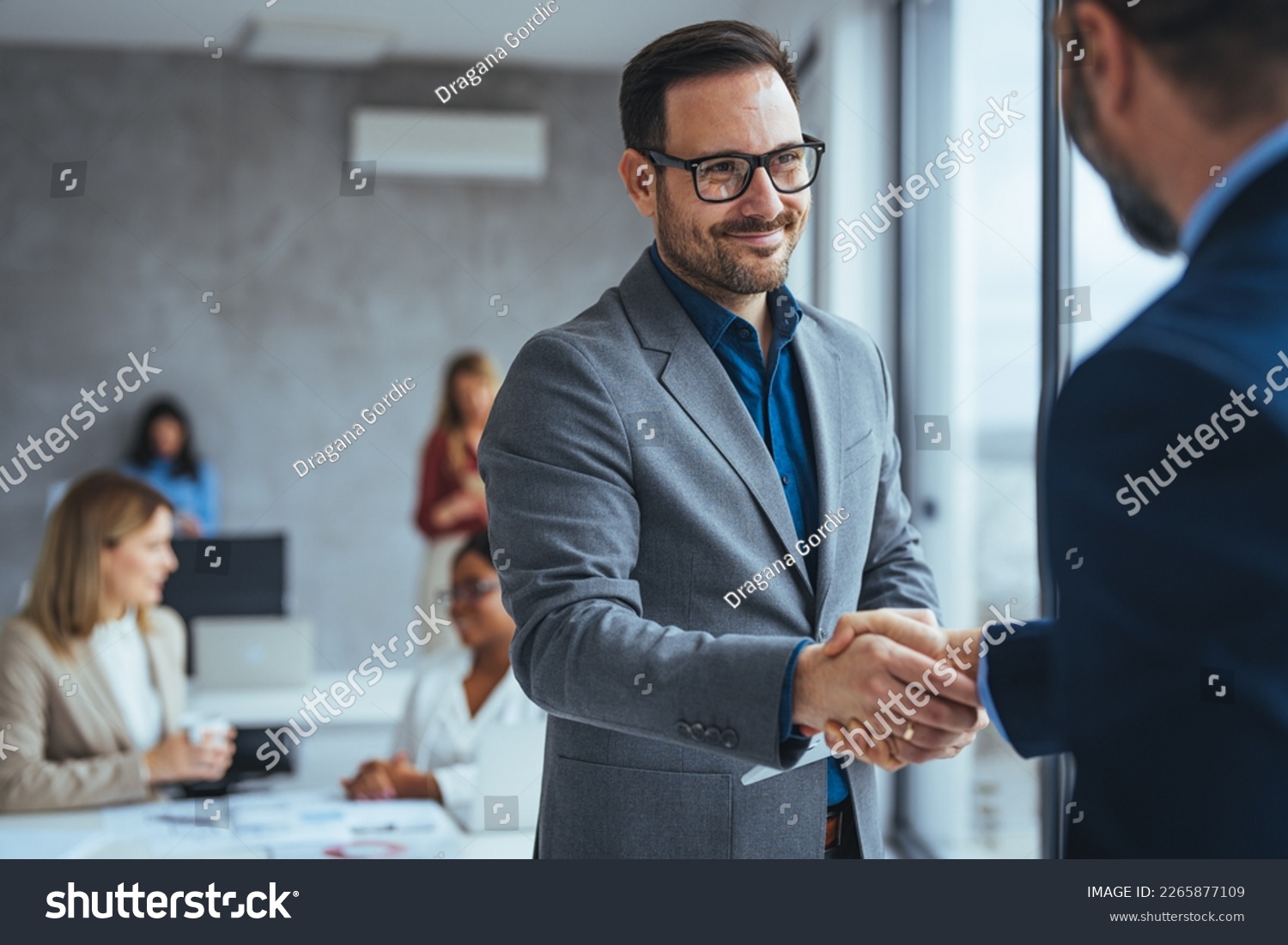 Portrait of cheerful young manager handshake with new employee. Business partnership meeting in office. Close up of handshake in the office. Mature businessman shake hands with a younger colleague #2265877109