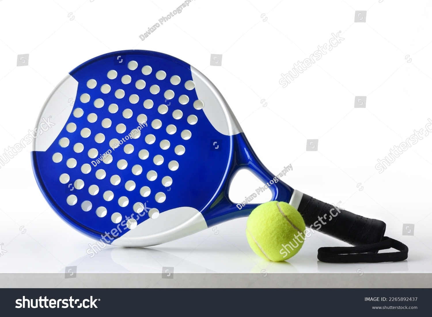 Padel racket and ball reflected on white table and white isolated background. Front view. #2265892437