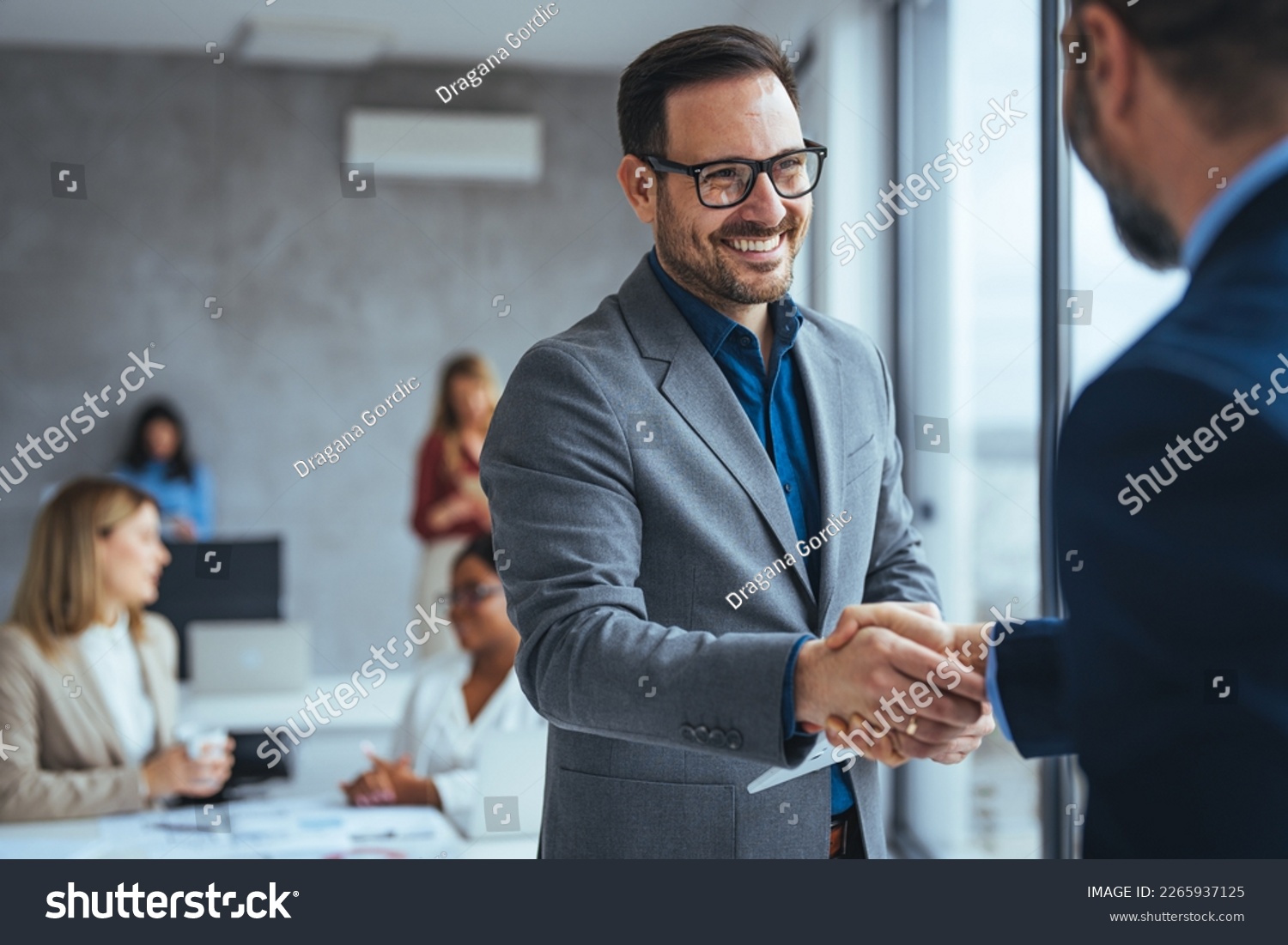 Shot of two businessmen shaking hands in an office. Two smiling businessmen shaking hands while standing in an office. Business people shaking hands, finishing up a meeting #2265937125