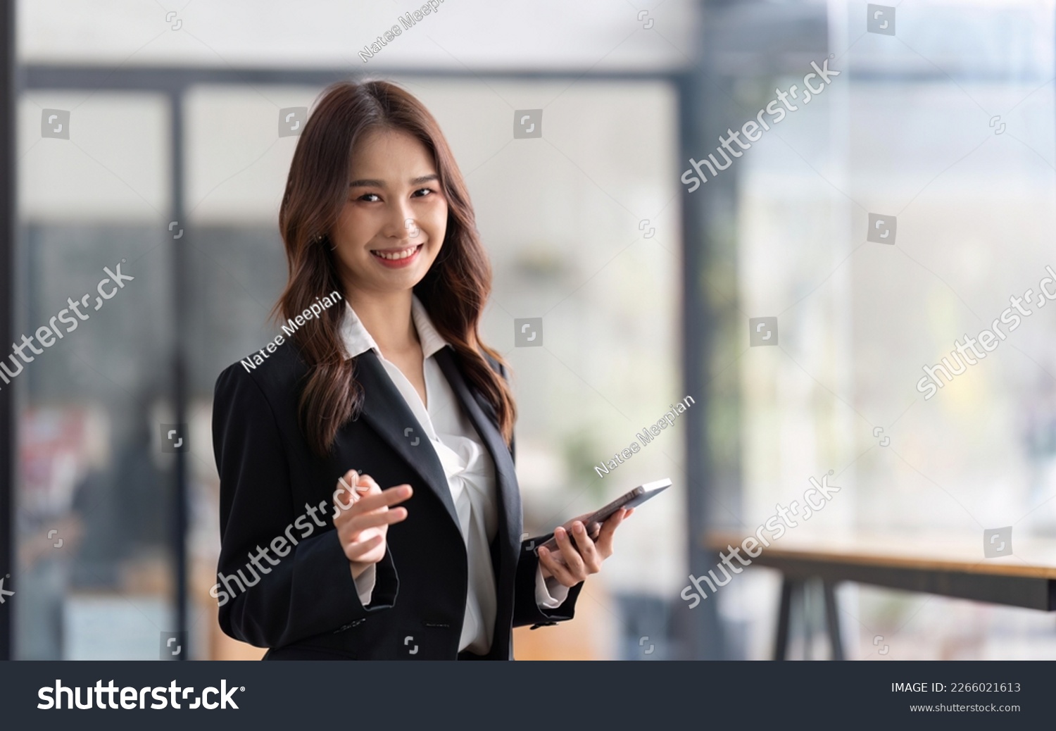Happy businesswoman holding telephone working standing in office using mobile cell phone working #2266021613