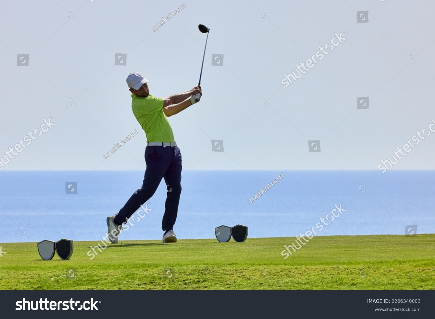Golfer on a golf course, ready to tee off. Golfer with golf club hitting the ball for the perfect shot. #2266340003