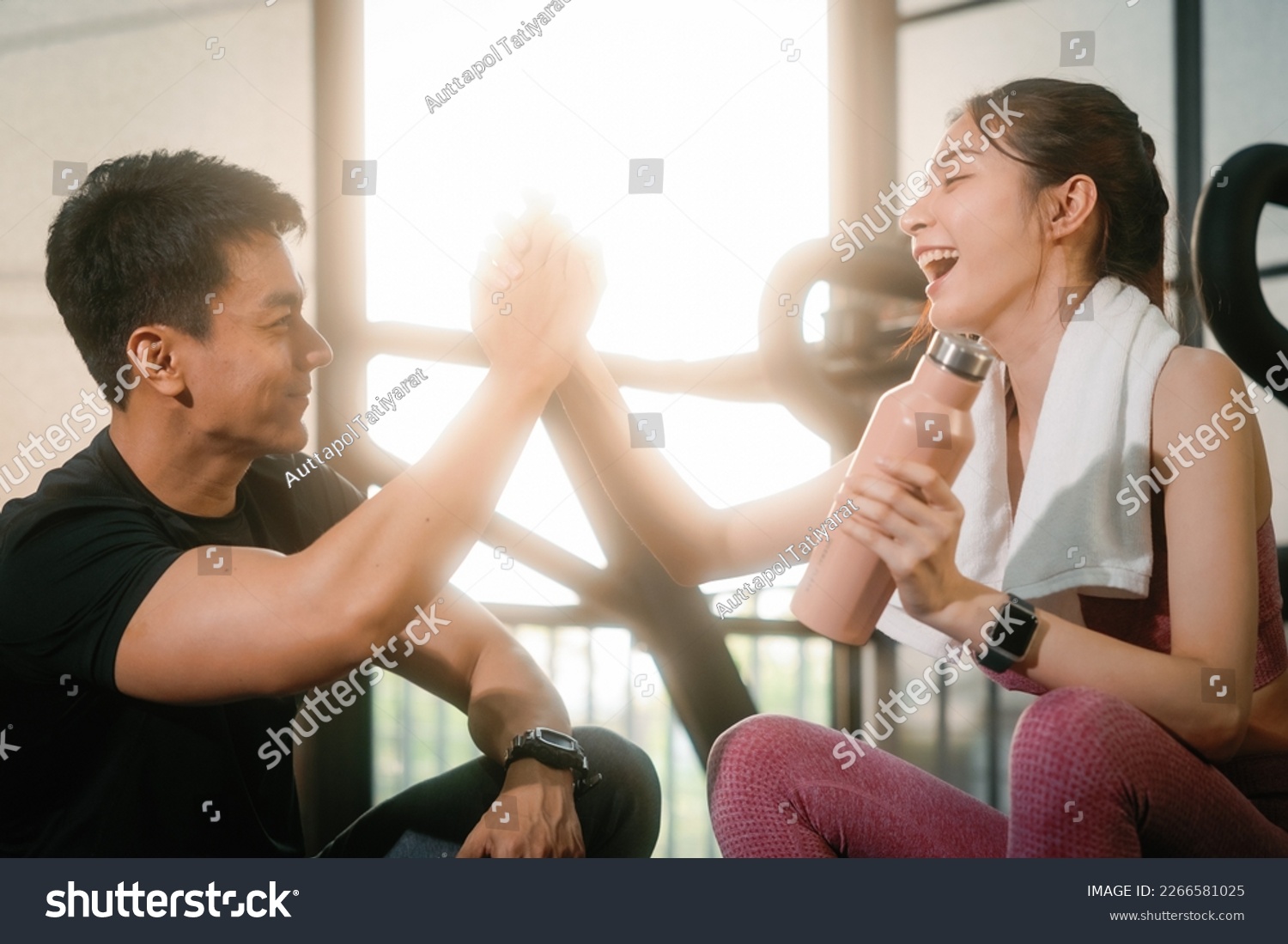 Young slim fitness Asian woman sitting and shake hands with personal trainer conversation for a break in the gym. The athlete leads a healthy lifestyle. Cardio training for weight loss. #2266581025