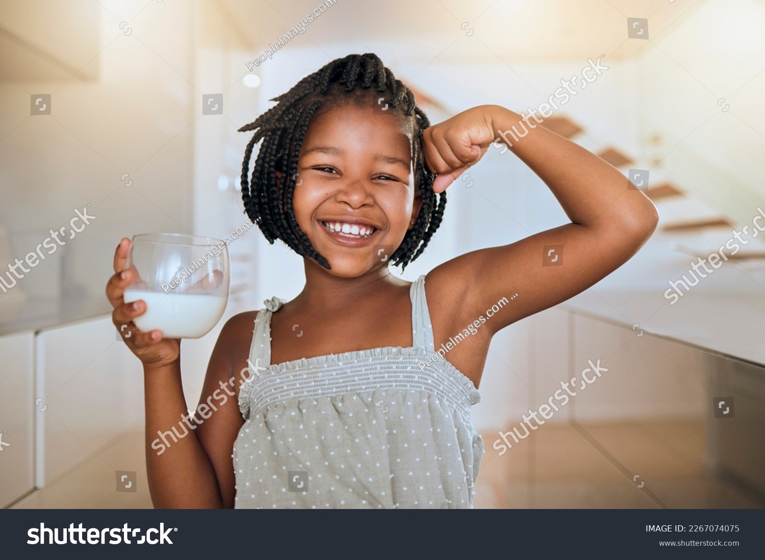 Milk, portrait and African girl with muscle from healthy drink for energy, growth and nutrition in the kitchen. Happy, smile and child flexing muscles from calcium in a glass and care for health #2267074075