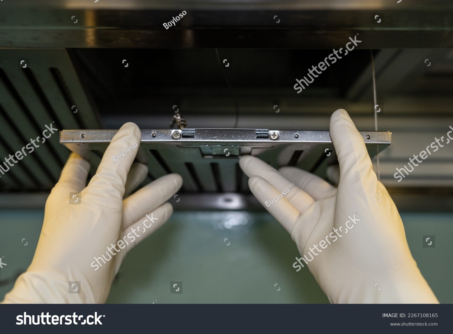Someone hands trying to removing a filters from cooker hood for cleaning it. Clean your filters every two to three months, depending on your cooking habits. #2267108165