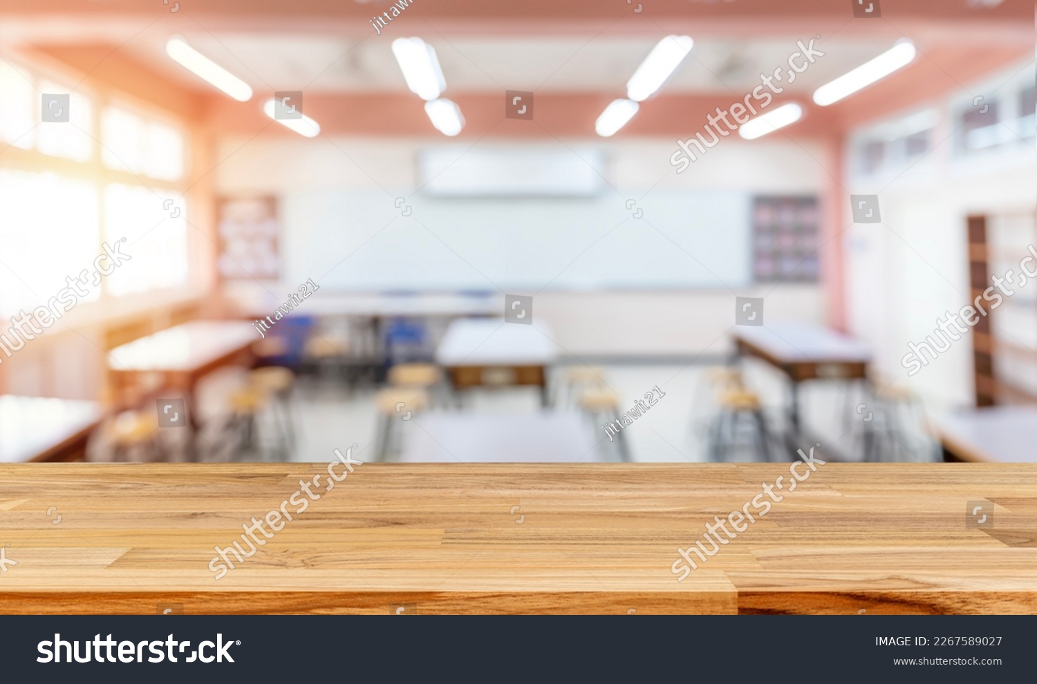 Cropped shot of wooden table with books, stationery and copy space in blurred study room.Empty classroom or presentation room interior with desks, chairs and whiteboard #2267589027