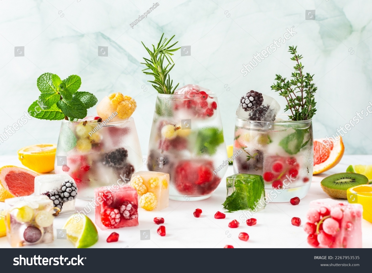 Refreshing drinks with ice cubes with fruits and citrus fruits, ice with blackberries and raspberries, gooseberries and currants, with mint, a jug of water and citrus fruits #2267953535
