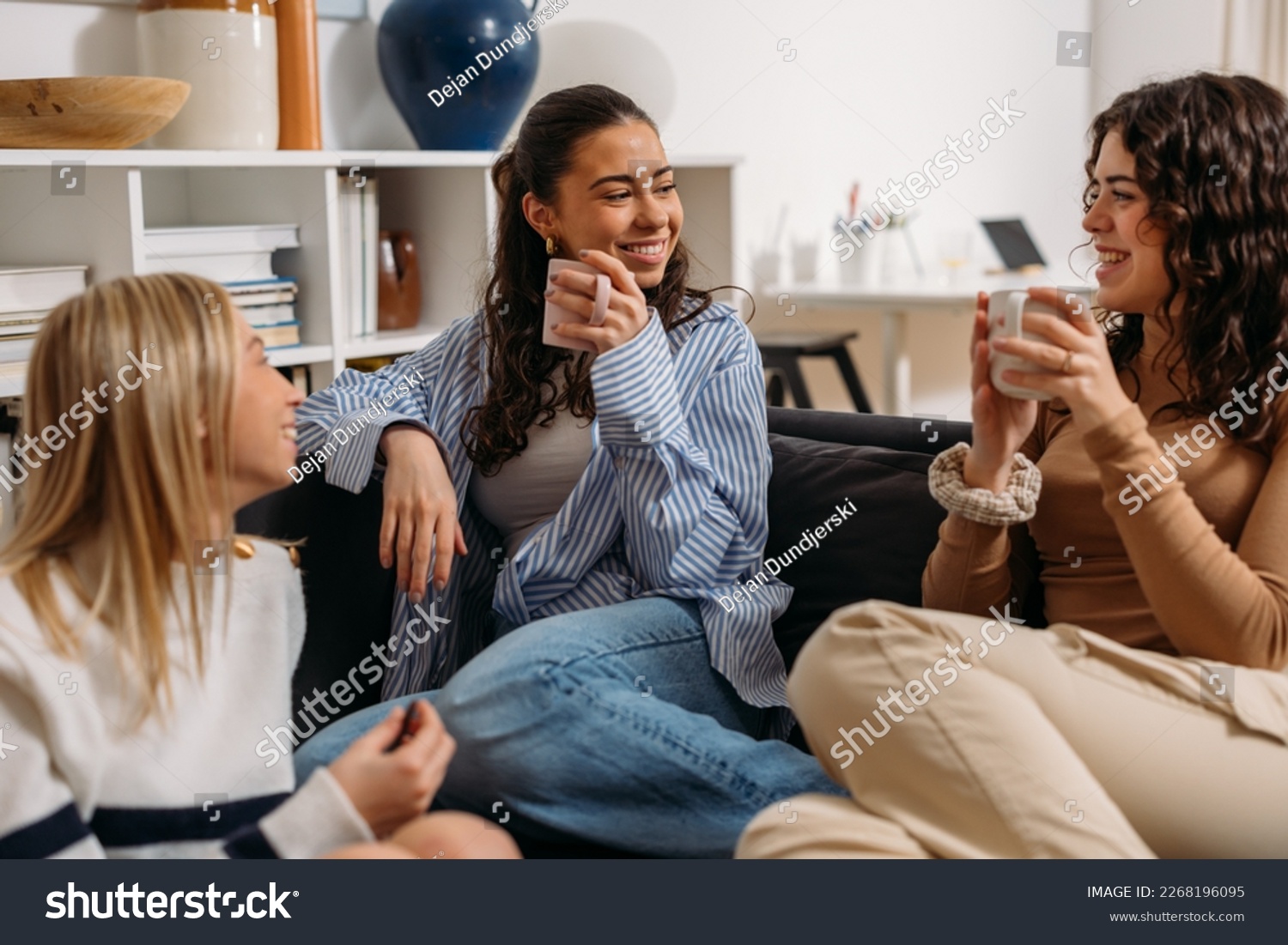 Three female friends are having an enjoyable conversation over coffee #2268196095