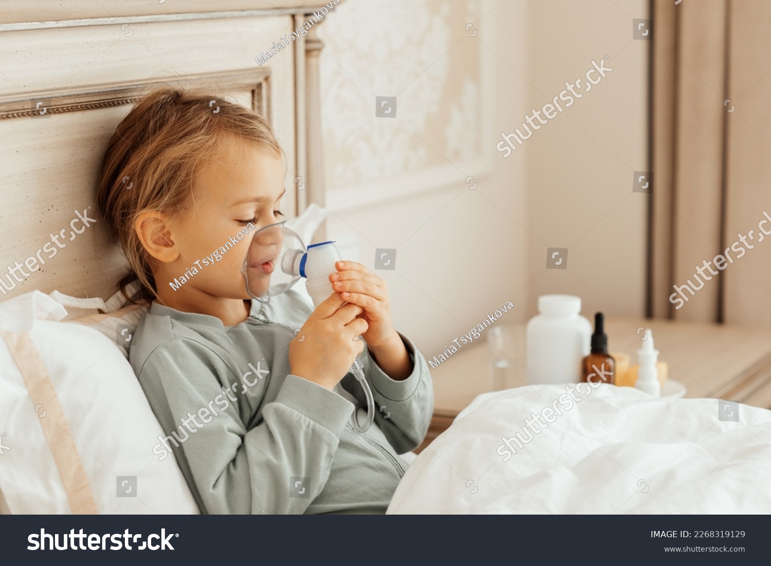 Little girl kid making inhalation with nebulizer at home at bed. child asthma inhaler inhalation steam sick pacient inhaling through inhaler mask. Self treatment of the respiratory tract #2268319129