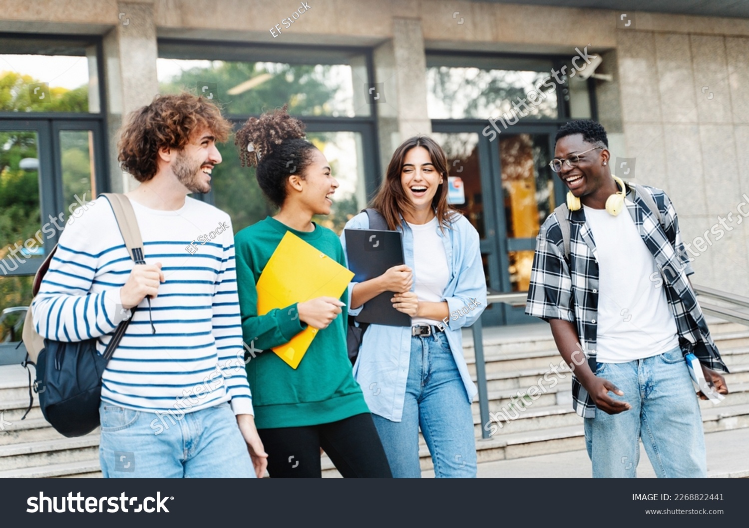 Happy international university friends walking together in campus, chatting and laughing outdoors after school #2268822441