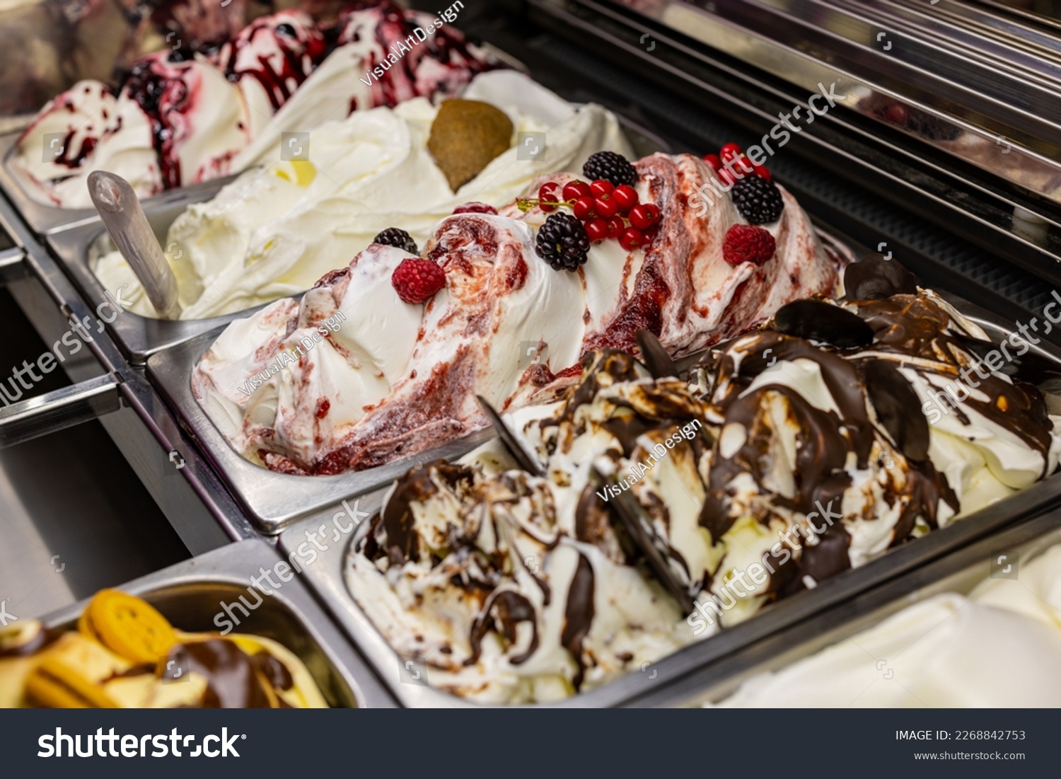 Tubs of ice cream of various flavors photographed in an ice cream parlor ready to be sold #2268842753