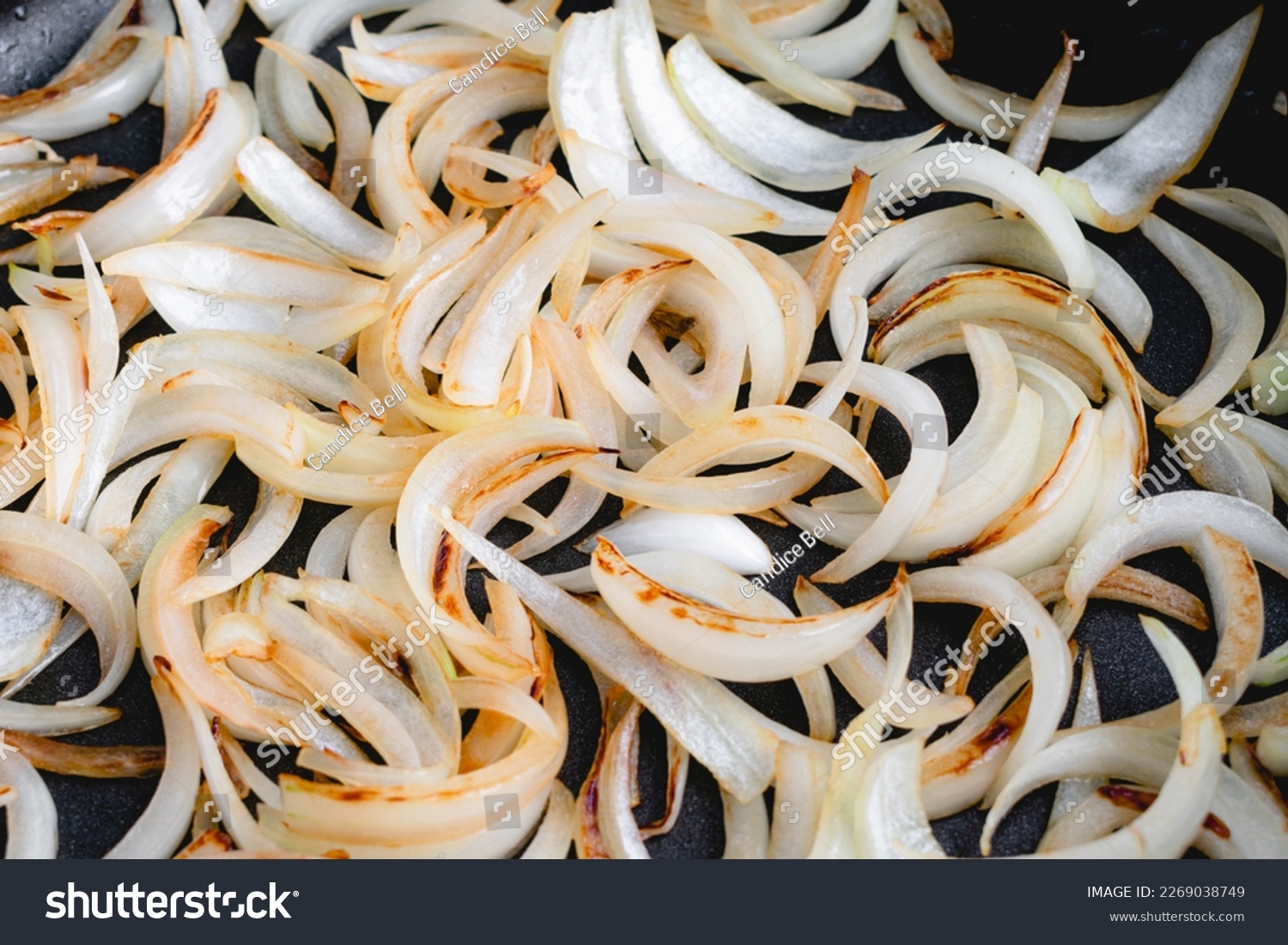 Close Up View of Sliced Onions Browned in a Skillet: Slices of sweet onion cooked in olive oil browning in a frypan #2269038749