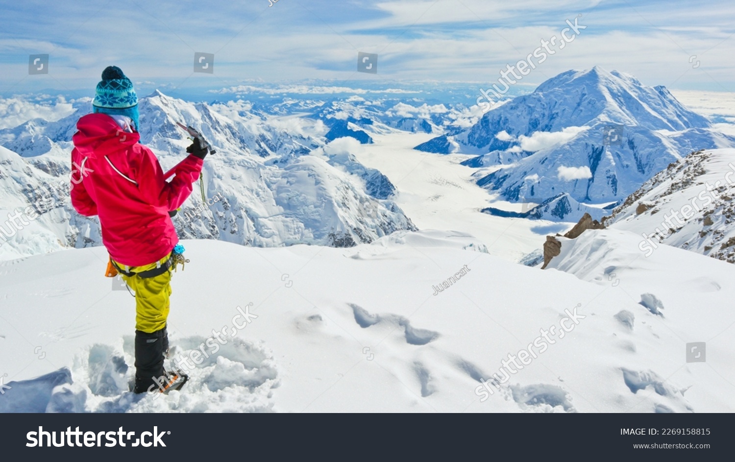A female climber with ice axe enjoying panoramic view on Mt Denali in Alaska, the highest mountain in North America #2269158815