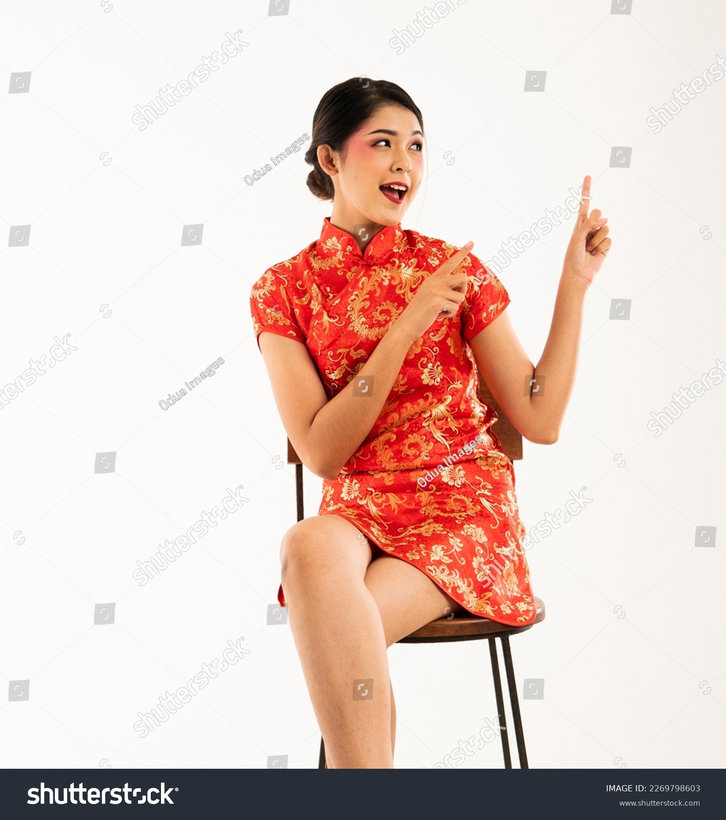 a beautiful asian woman in red cheongsam sitting and pointed to her side with her forefinger #2269798603