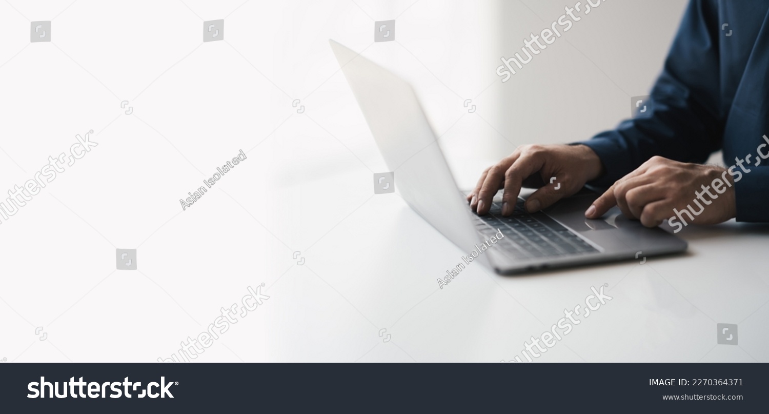 Cropped shot of young businessman hand typing on laptop computer while working in white modern office room. #2270364371