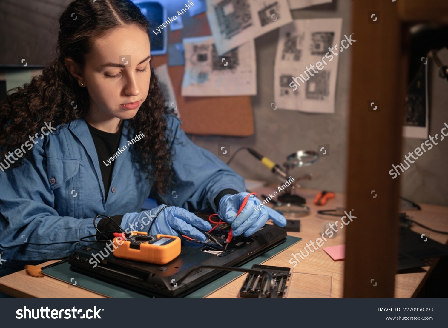 Concentrated female technician busy repairing laptop and it testing with multimeter at retro workshop. Concept of professional worker and repair service. #2270950393