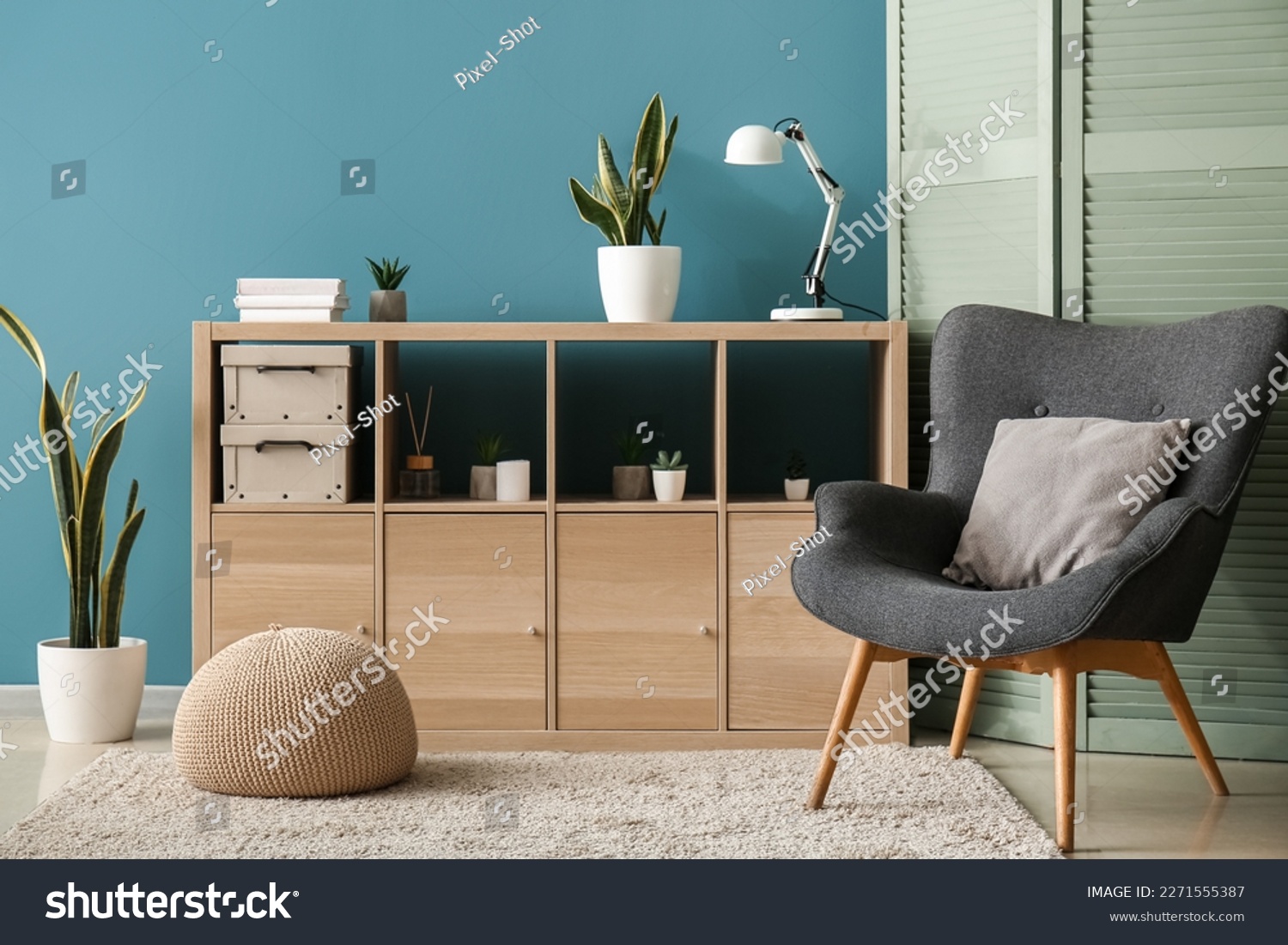 Interior of cozy living room with folding screen, armchair and drawers #2271555387