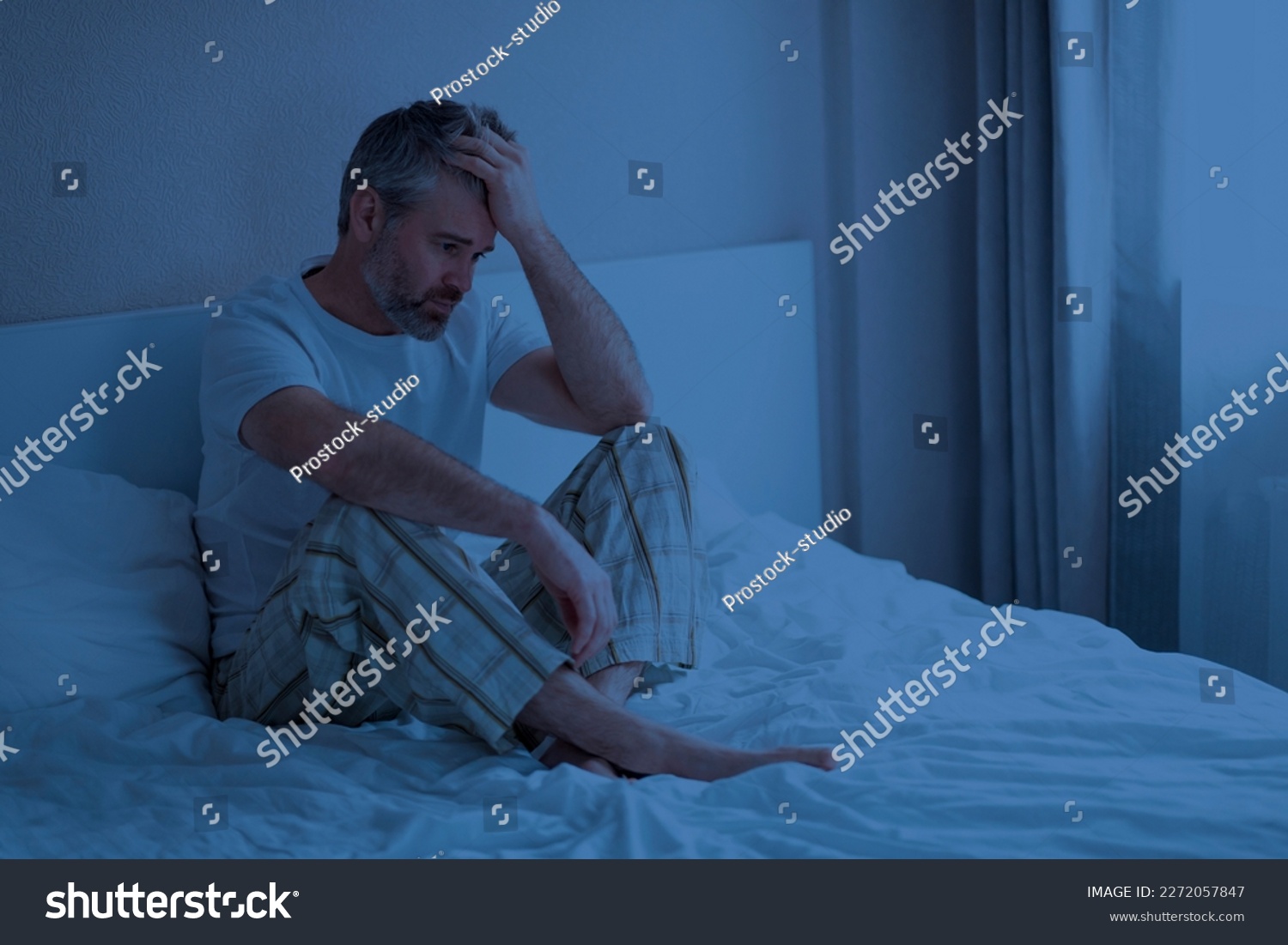 Sleep disorders. Stressed upset thoughtful handsome middle aged man wearing pajamas sitting on bed at night, touching head, awake from bad dream, suffering from nightmares, home interior, copy space #2272057847