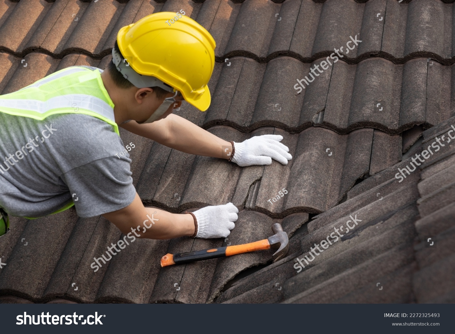 Worker man replace tile of the old roof. Repair roof concept. #2272325493