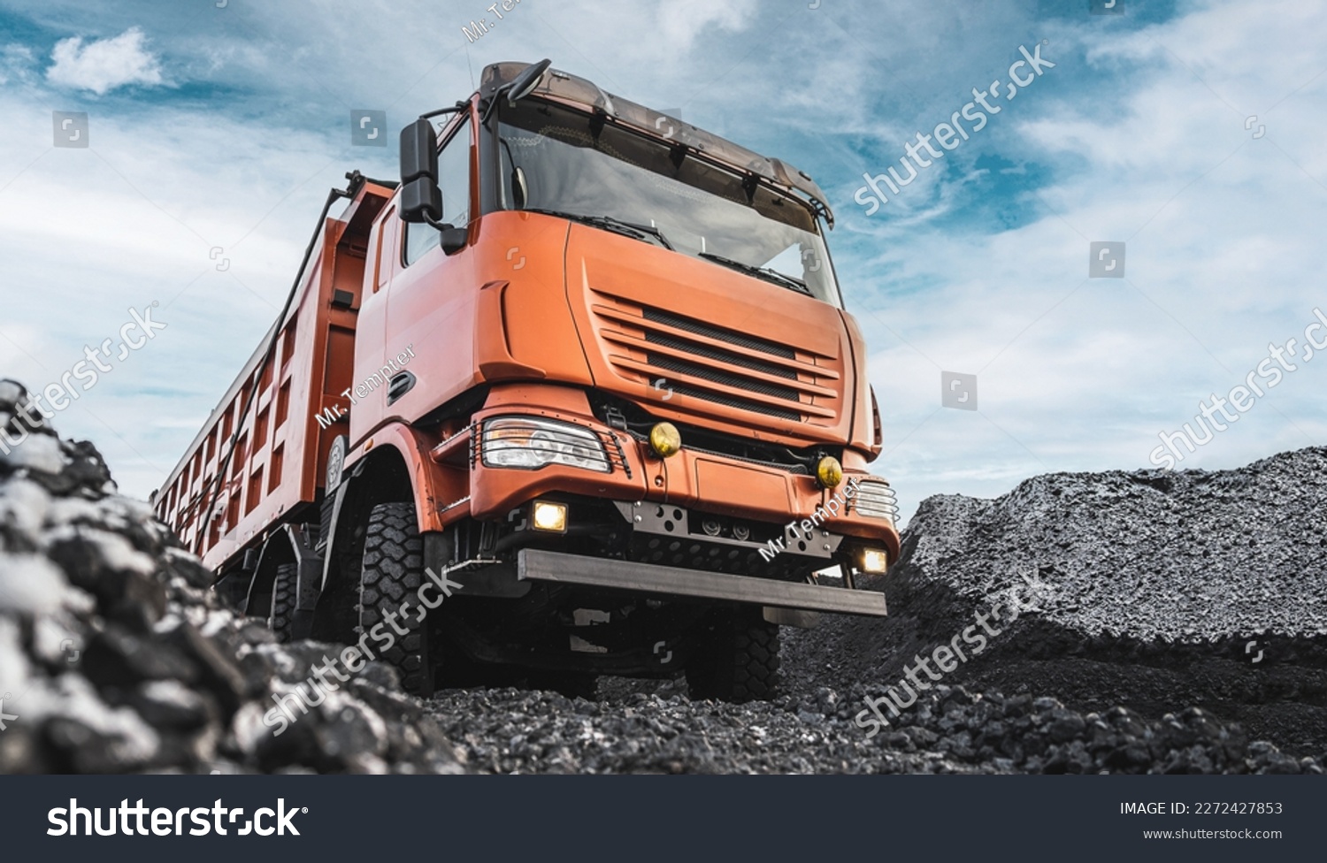Large quarry dump truck. Dump truck carrying coal, sand and rock. Trucks moving on dirt country road in forest. Mining truck mining machinery to transport coal from open-pit. Transportation of mineral #2272427853