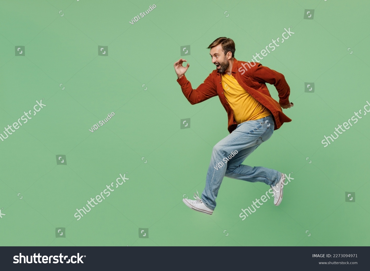Full body side view happy fun cheerful elderly man 40s years old he wear casual clothes red shirt t-shirt jump high run fast hurrying up isolated on plain pastel light green background studio portrait #2273094971