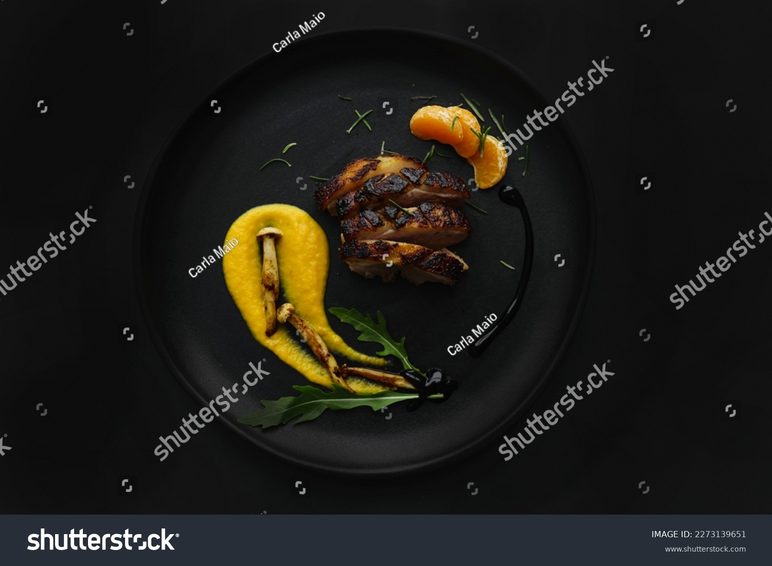 Dark photo of a fine dining dish with duck breast and roasted squash purée, mushrooms and greens. Black background with studio professional lighting in a top view, flat lay. Stylish gourmet plating. #2273139651