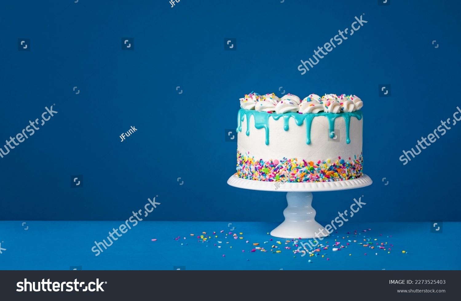 White birthday drip cake with teal ganache over dark blue background #2273525403