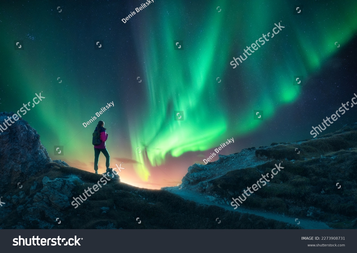 Northern lights and young woman on mountain peak at night. Aurora borealis and silhouette of alone girl on mountain trail. Landscape with polar lights. Starry sky with bright aurora. Travel background #2273908731