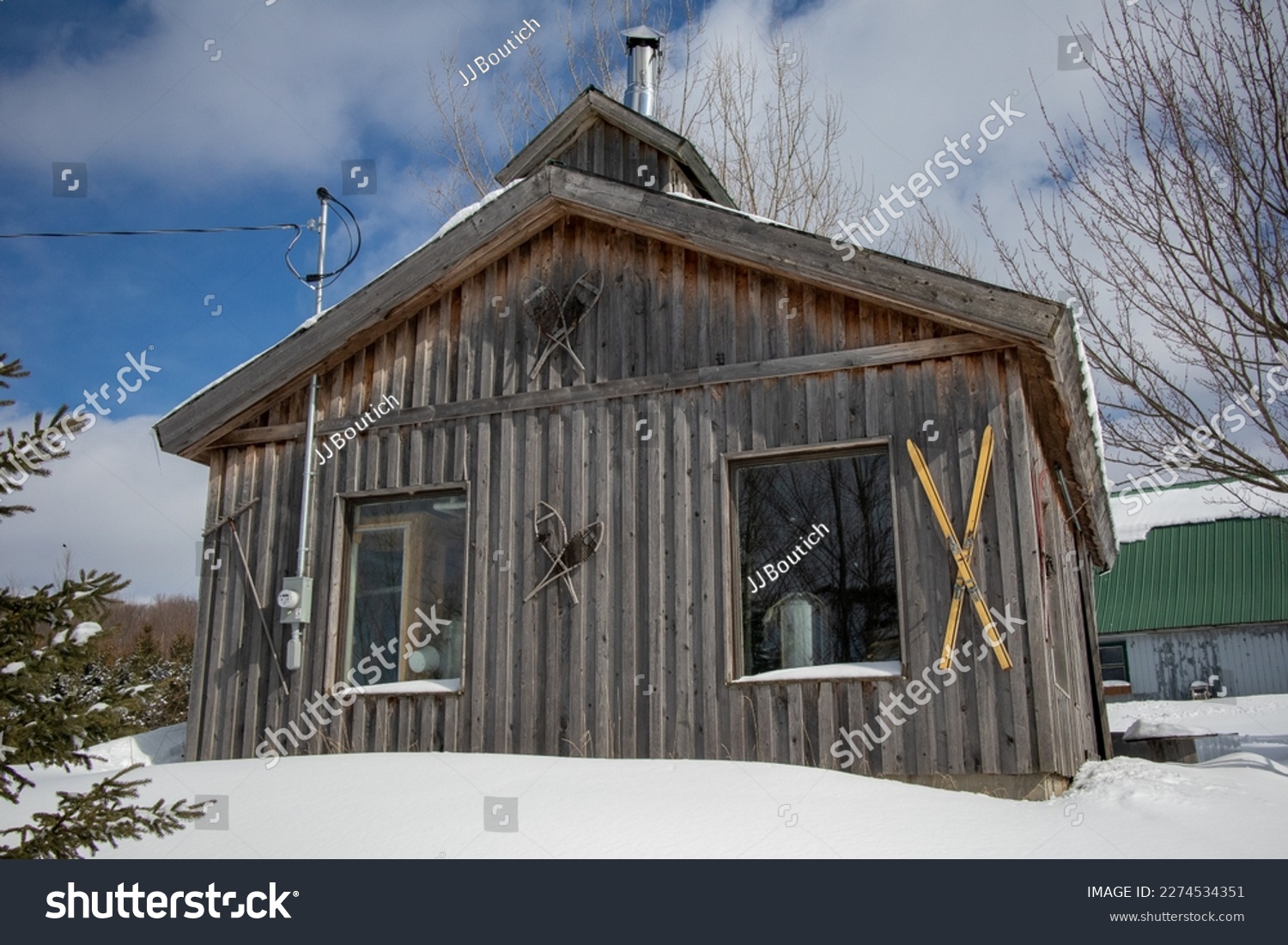 Sugar shack, old traditional barn in Quebec, Canada, surrounded by snow with vintage ski decoration #2274534351