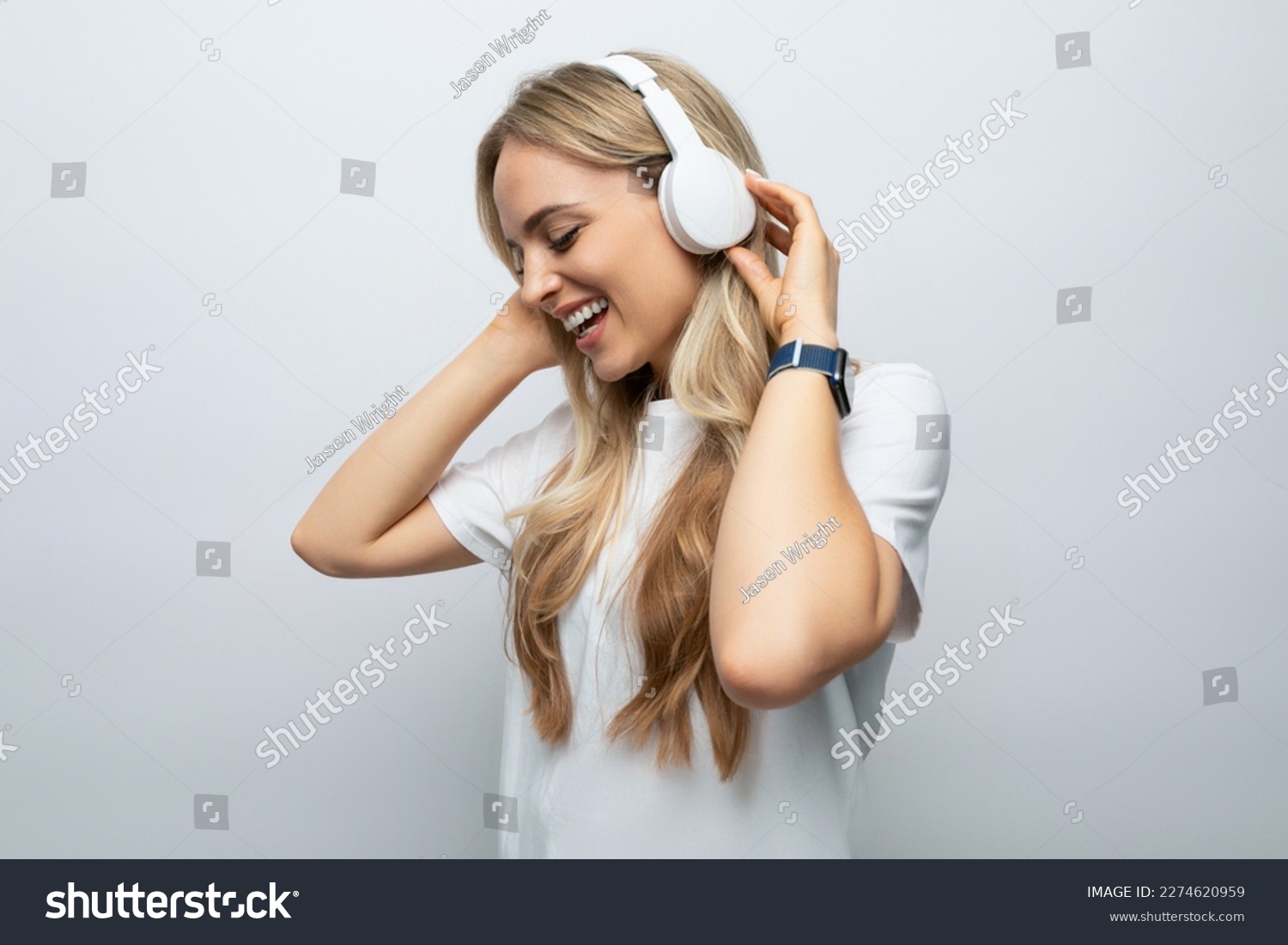 romantic woman sings along to music from headphones among white background #2274620959