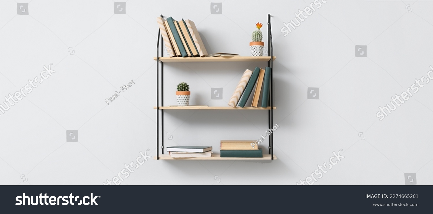 Modern shelves with books and cacti hanging on light wall #2274665201