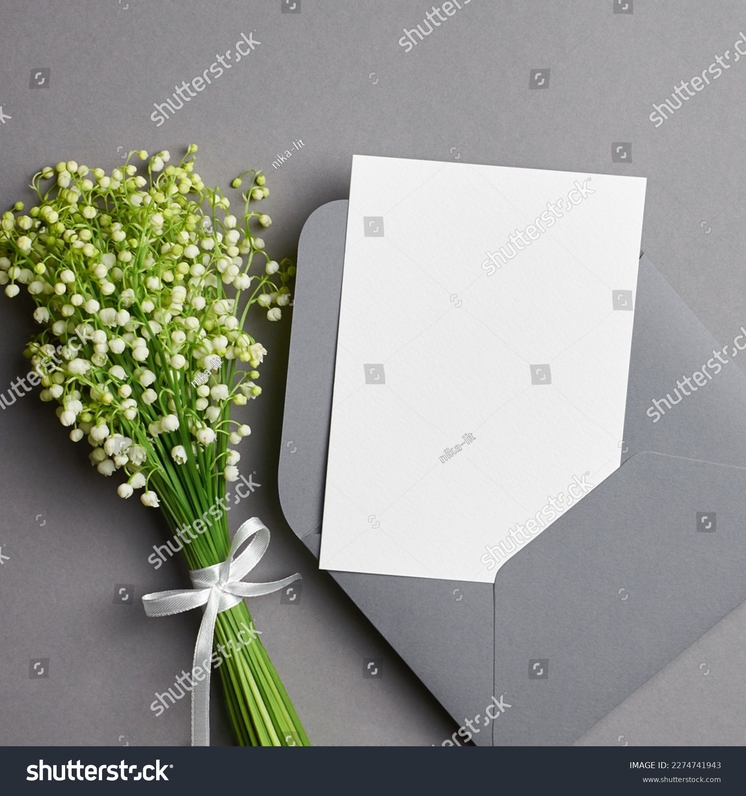 Blank wedding invitation card mockup with white lily of the valley flowers on grey background #2274741943