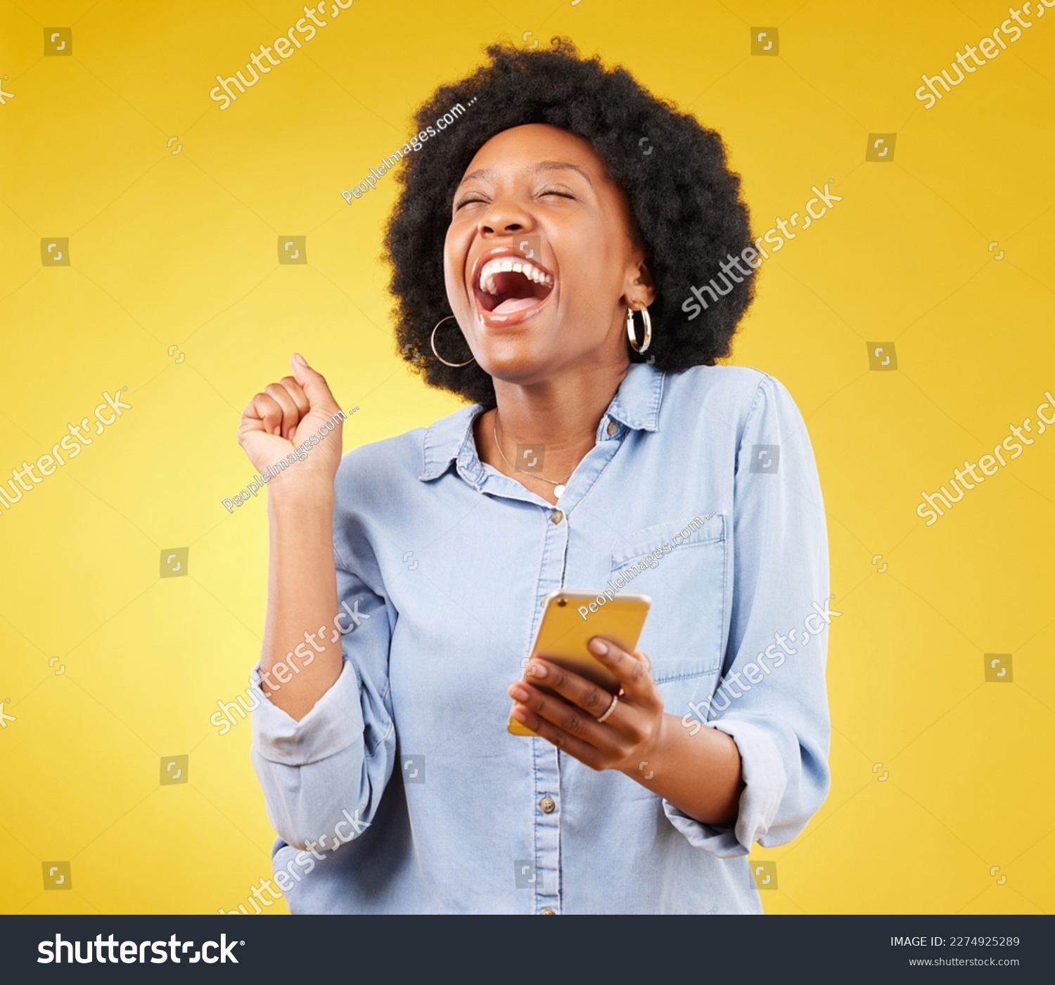 Happy, excited and phone with black woman in studio for text message, notification and social media news. Deal, winner and celebration with girl on yellow background for offer, giveaway and surprise #2274925289