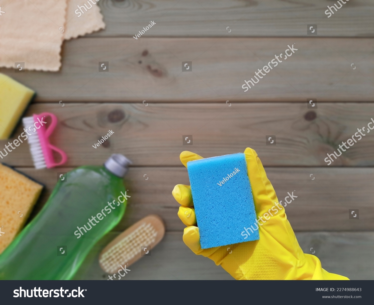 Kitchen sponge in hand. Flat lay. Concept of spring Deep clean of house. Place for text.  Rubber glove with washcloth on blurred background of wooden table with cleaning tools. Copy space. Top view. #2274988643