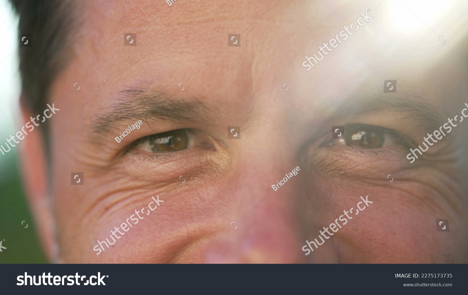 One happy man macro portrait face close up smiling outside with sunlight flare. 40s person with wrinkles closeup of eyes #2275173735