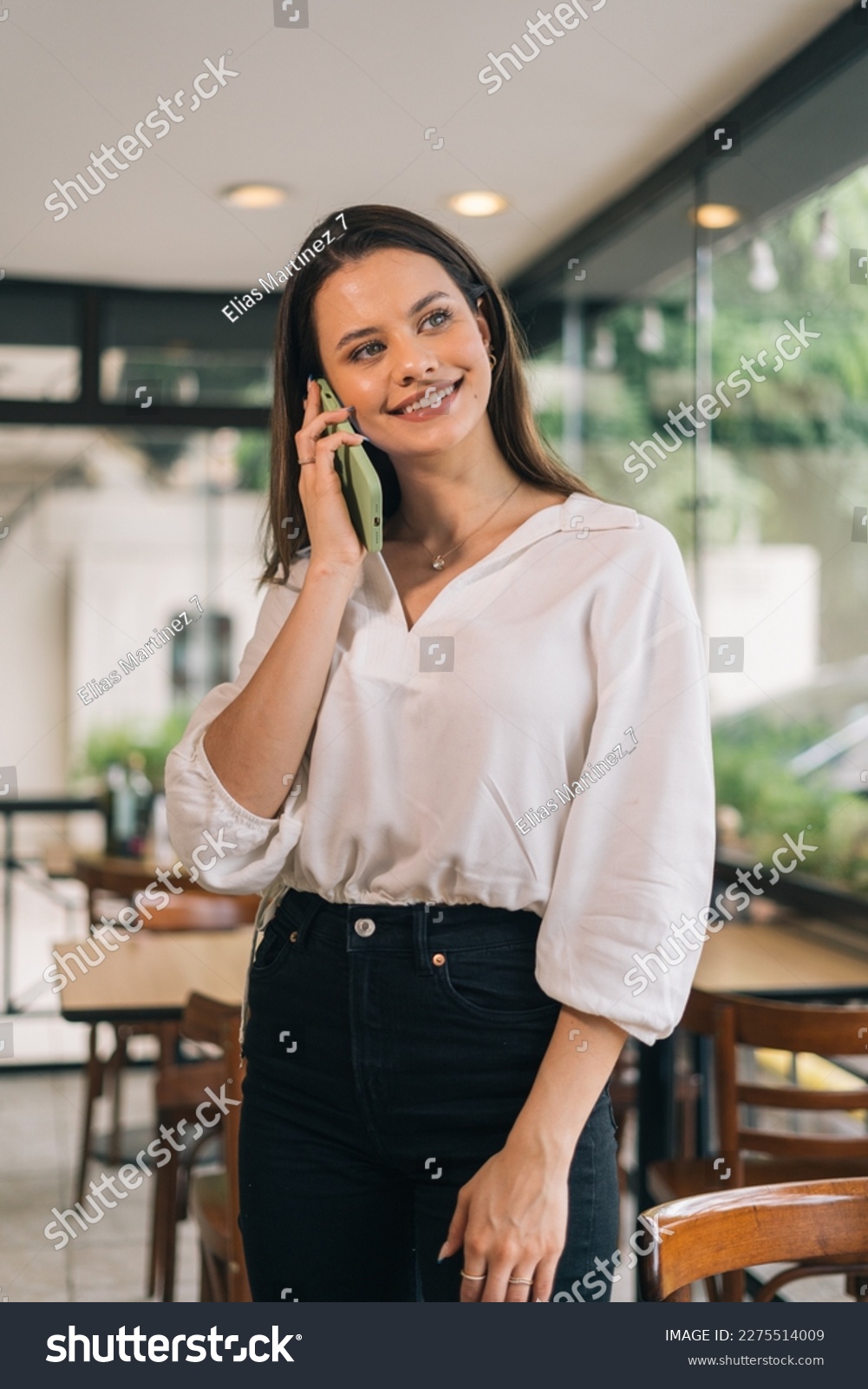 Concept of smiling woman making calls with a telephone in her office. Vertical photo of a person taking order on the phone #2275514009