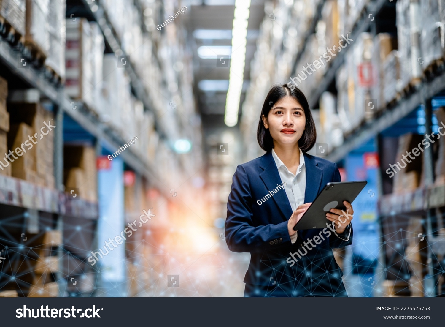 Business women use a digital tablet to manage the stock inventory on shelves in the large warehouse, smart cargo management system, supply chain and logistic network technology concept. #2275576753