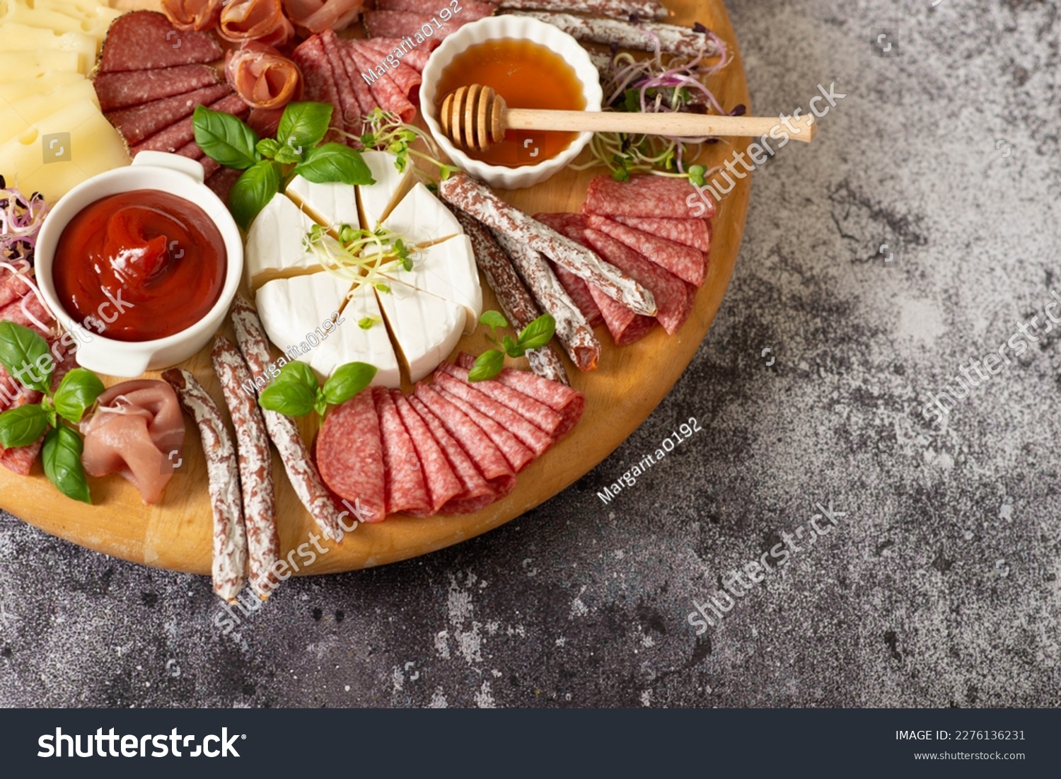 Wooden plate with delicacies. Brie cheese, blue cheese, salami, prosciutto on a wooden board. sausage, cheese, honey. plate of delicacies #2276136231