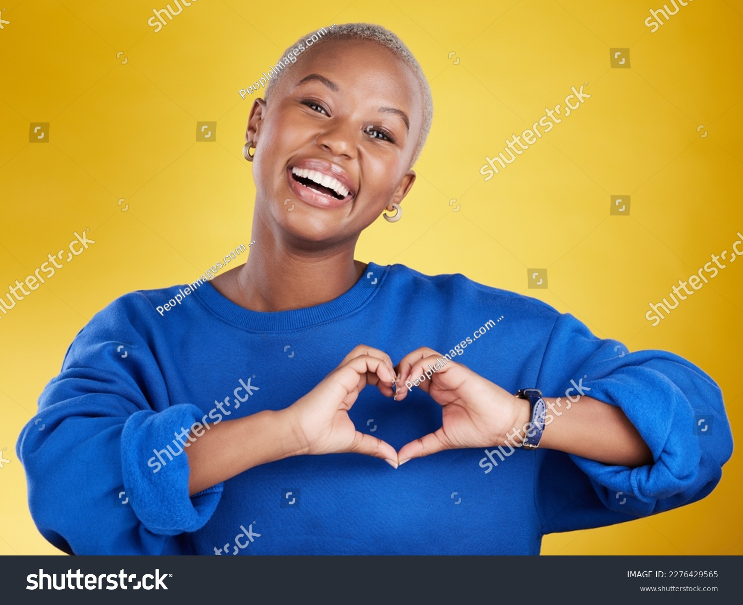 Heart hands, portrait and happy black woman in studio, background and color backdrop for emoji. Smile, female model and finger shape for love, thank you and support of peace, care or sign of kindness #2276429565