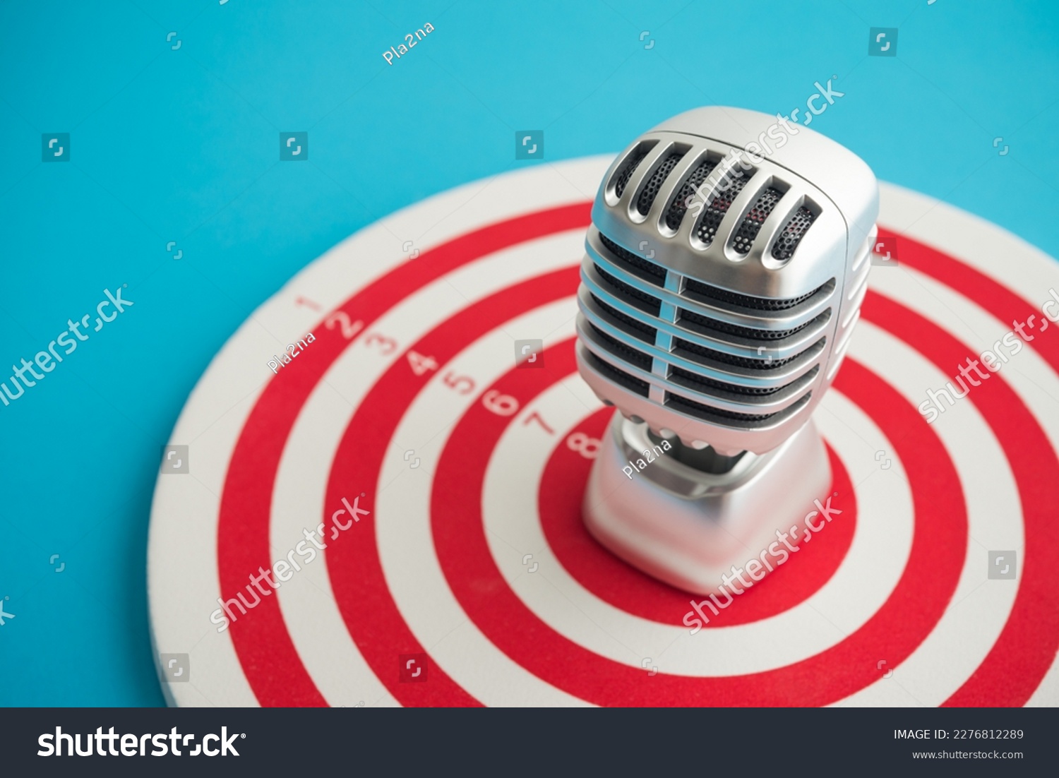 Retro microphone on center of target blue background copy space. Focus on customer feedback, satisfaction, review need for organization improvement and development. Leadership management and strategy. #2276812289