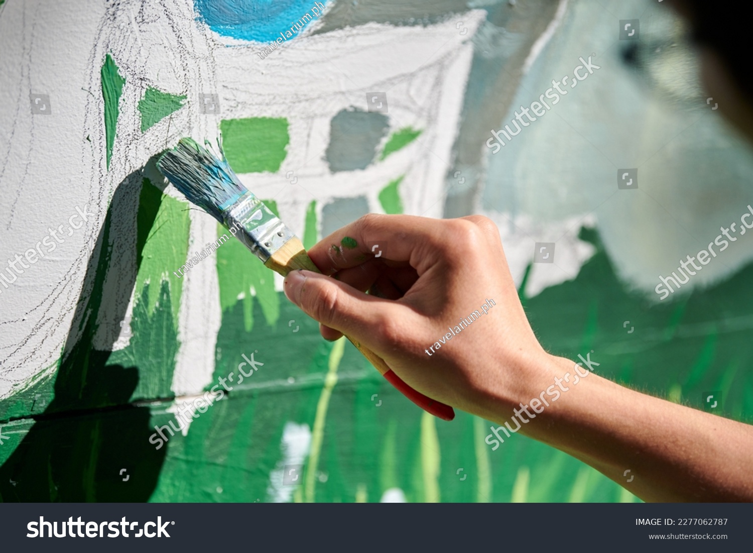 Girl artist hand holds paint brush and draws green nature landscape on white canvas at outdoor art painting festival, paintings art picture process. Woman artist paints atmospheric surreal picture #2277062787