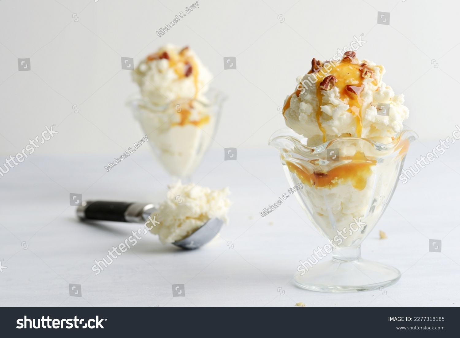 scoops of vanilla ice cream with pecans and caramel sauce #2277318185
