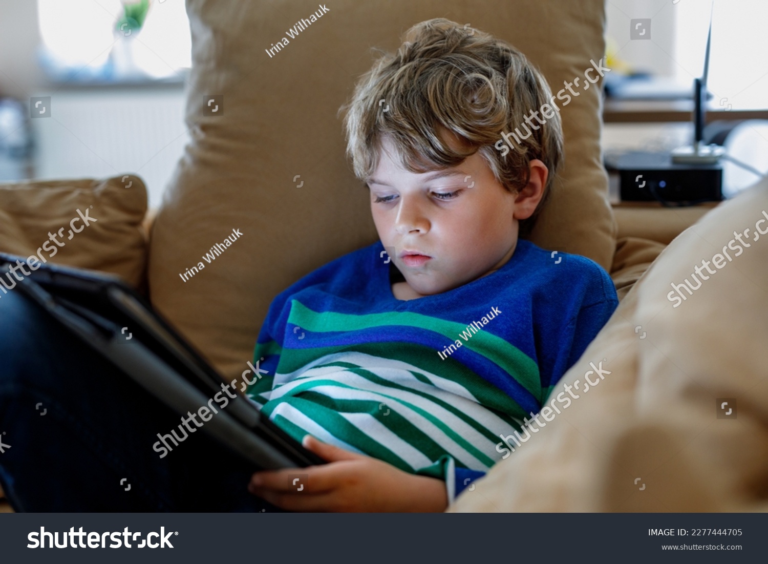 School boy with tablet computer. Schoolchild study online. Electronic device for learning, studying and playing at home. Little boy with laptop pc. Gadget and screen time for children. Kid at home. #2277444705