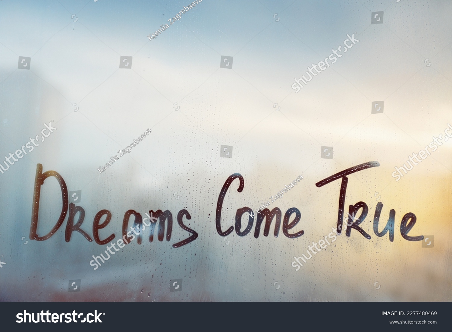 Handwritten message wish Dreams come true on misted glass on sunset window with raindrops #2277480469