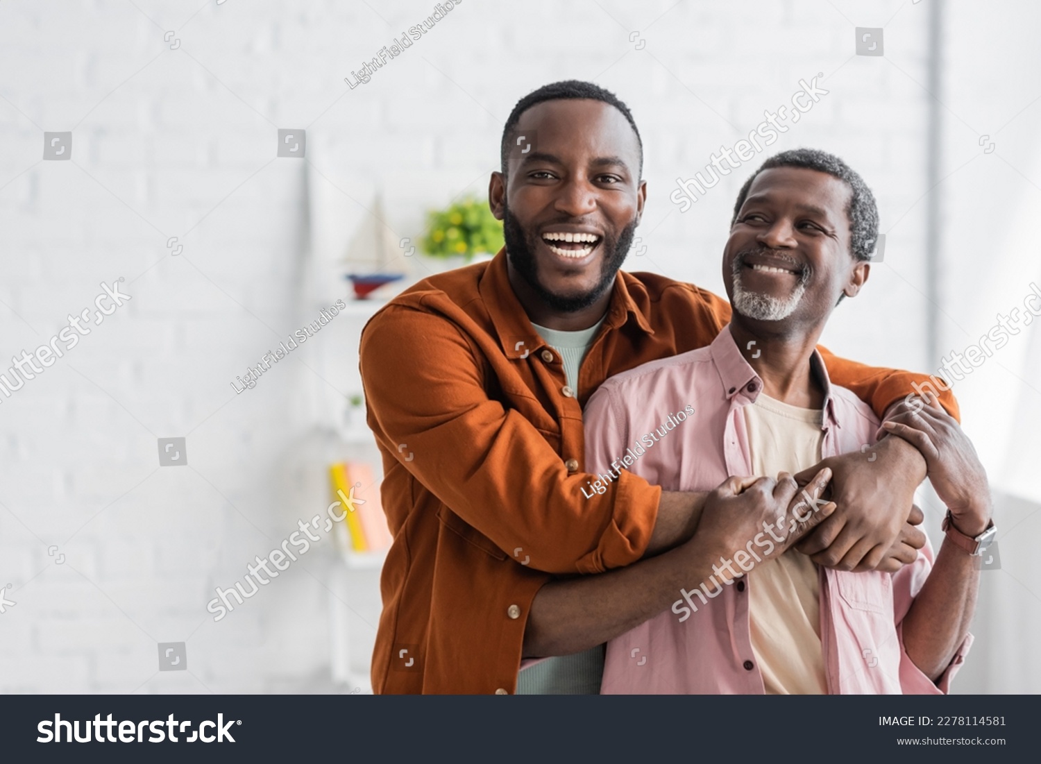 Cheerful african american man hugging mature dad and looking at camera at home #2278114581
